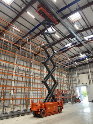 66 ft narrow scissor lift working at height indoors for maintenance.